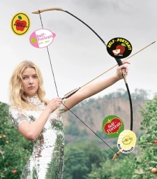 Model Apple Martin holding a traditional bow and arrow in an outdoor orchard setting for the Self-Portrait Fall-Winter 2025 campaign.