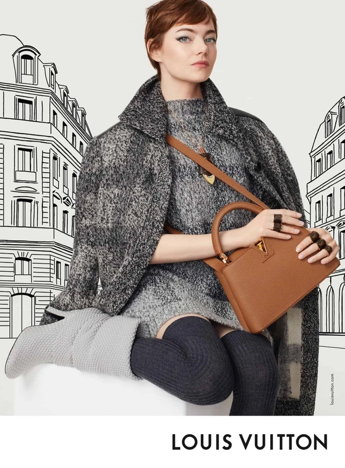 Emma Stone in a grey textured coat holding a brown leather handbag against an illustrated architectural background.