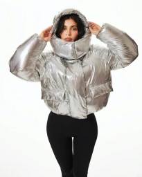 Kylie Jenner wearing a shiny metallic silver puffer jacket with a large hood against a plain white background.