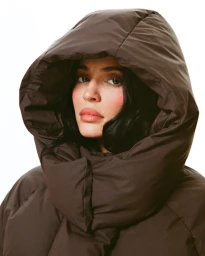 Kylie Jenner wearing a dark brown hooded puffer jacket against a clean white background for Khy Fall 2025.