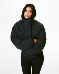 Kylie Jenner wearing a dark puffer jacket and black leggings against a clean white background for Khy Fall 2025.