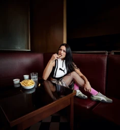Amelia Gray in a black and white Puma top eating fries in a diner booth