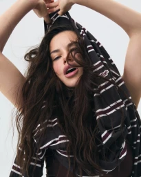 Adriana Lima lifting a dark striped top over her head against a plain white background for Adanola Ultimate Uniform