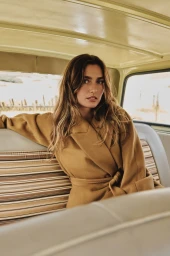 Andreea Diaconu seated inside a vehicle wearing a camel coat for Banana Republic October Edit