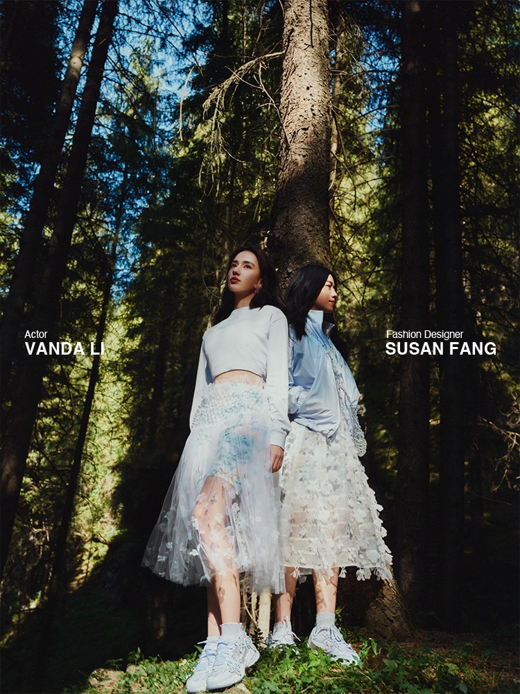 Vanda Li and Susan Fang posing in sheer white skirts and sneakers by a tall pine tree in a sunlit forest for Nike.