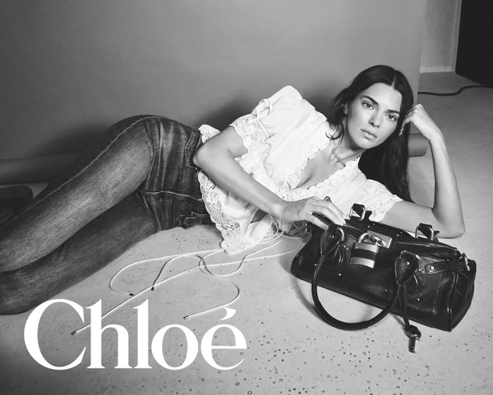 Kendall Jenner lying on a studio floor with a black leather handbag for a Chloe campaign