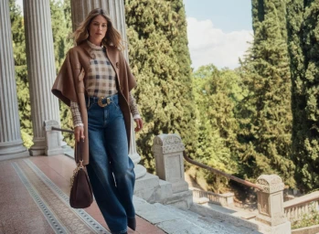 Model Doutzen Kroes wearing a brown cape, plaid top, and jeans on a colonnade terrace for Twinset Fall-Winter 2025 campaign.