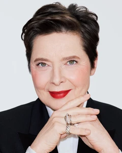 Close-up portrait of Isabella Rossellini wearing a black blazer and red lipstick against a plain white background for Lancôme