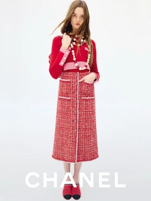Model Lulu Tenney in red tweed skirt and matching top with pearl necklaces against a white seamless background for Chanel Fall-Winter.
