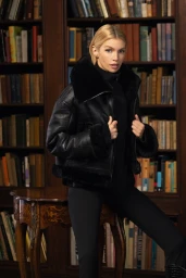 Stella Maxwell wearing a black shearling jacket in a wood-paneled library for Mackage Fall-Winter 2025 Campaign