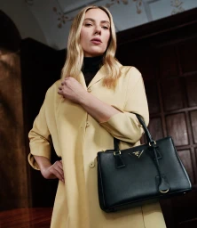 Scarlett Johansson holding a black handbag and wearing a yellow coat for Prada Galleria Ritual Identities