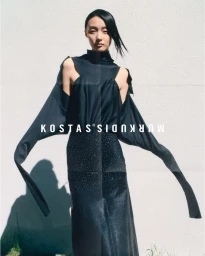 Asian woman in dark cutout top and sparkling skirt standing against a white wall