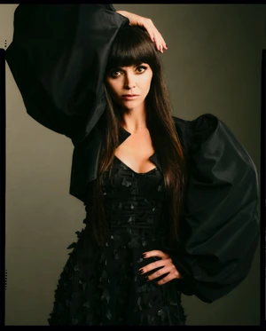 Christina Ricci in a black dress with voluminous puffy sleeves posing against a dark background for Betsey Johnson Fall 2025 Campaign