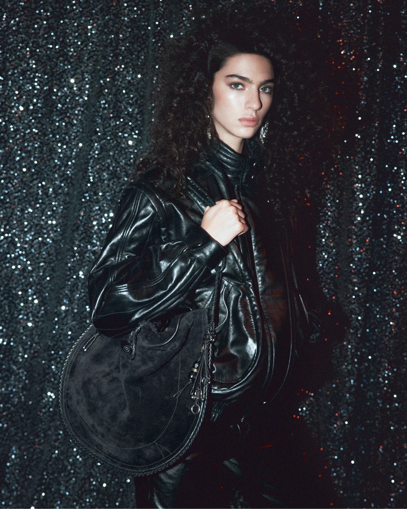 Loli Bahia wears a black leather jacket with a round suede shoulder bag against a glittering dark backdrop for Isabel Marant.