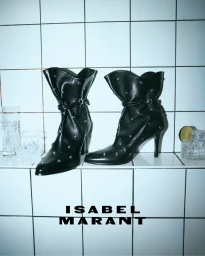 Black studded leather high-heel boots on a tiled shelf with glasses and lime