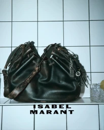 Isabel Marant dark leather slouchy shoulder bag sitting on a tiled surface beside a glass with ice.