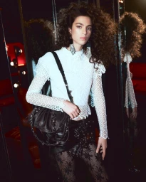 Loli Bahia wearing a white lace top and black leather skirt with a crossbody bag for Isabel Marant Fall-Winter 2025 campaign.