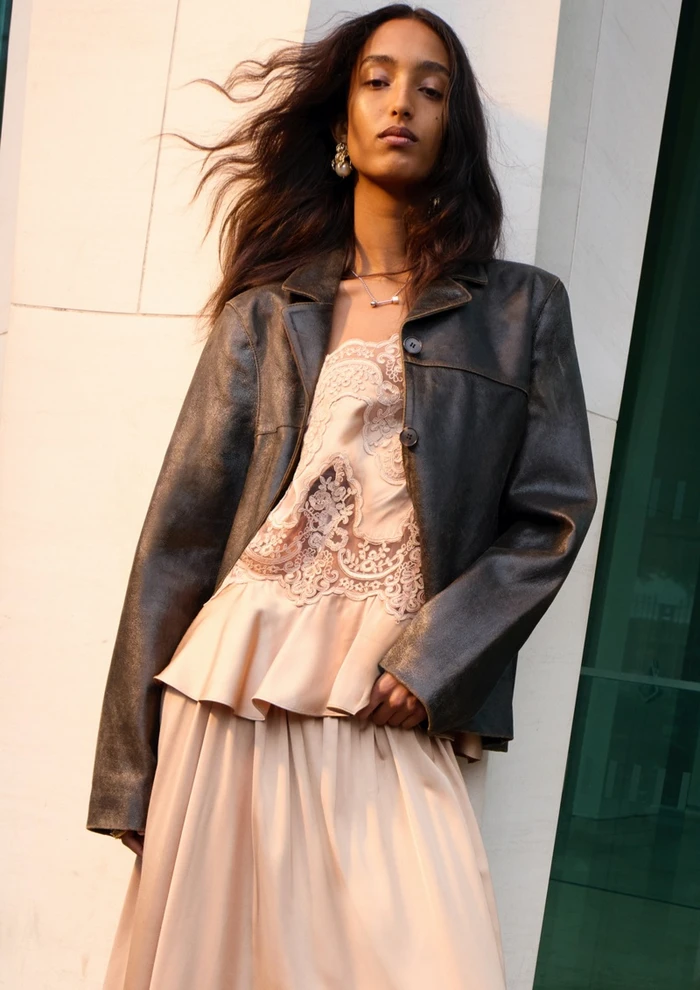 Mona Tougaard wearing a dark leather jacket over a lace-trimmed slip dress for the H&M Fall-Winter 2025 campaign.