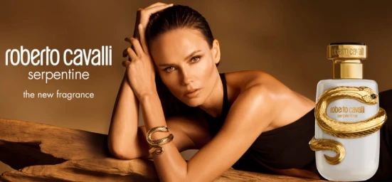 Natasha Poly leaning against wood posing with Roberto Cavalli Serpentine perfume bottle in campaign by Luigi & Iango