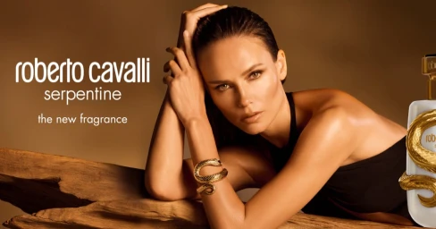 Natasha Poly wearing a gold snake bracelet leaning on a wooden branch for Roberto Cavalli Serpentine fragrance campaign