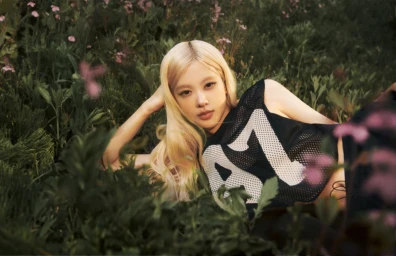 ROSÉ lying in a grassy meadow wearing a black mesh athletic top with white numbering for PUMA