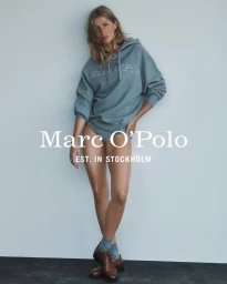 Gisele Bundchen wearing a blue hoodie and brown shoes against a plain grey studio backdrop for Marc O'Polo