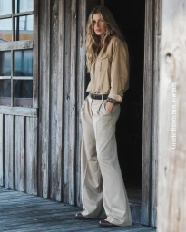 Gisele Bundchen standing in a doorway wearing a beige button-down shirt and wide-leg trousers for Marc O'Polo