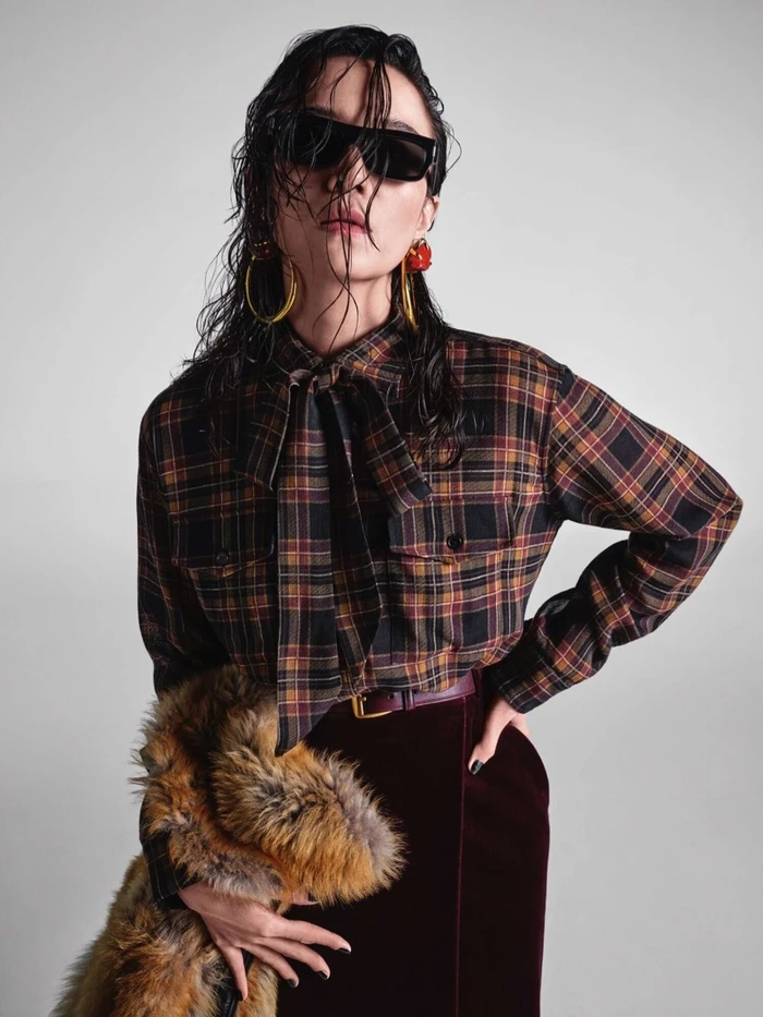 Model with wet hair wearing sunglasses, plaid shirt, and velvet skirt for Yves Saint Laurent Fall 2025 campaign