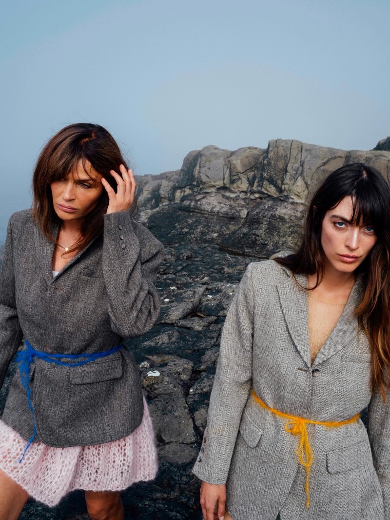 Helena Christensen and Louise Follain wearing belted grey wool blazers on a rocky shoreline for Gudrun & Gudrun.