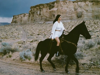 Kendall Jenner riding a black horse through a desert landscape for Alo campaign