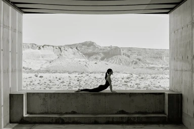 Kendall Jenner doing yoga in black activewear on a concrete ledge framing a desert mountain landscape for Alo Luxury Is Wellness