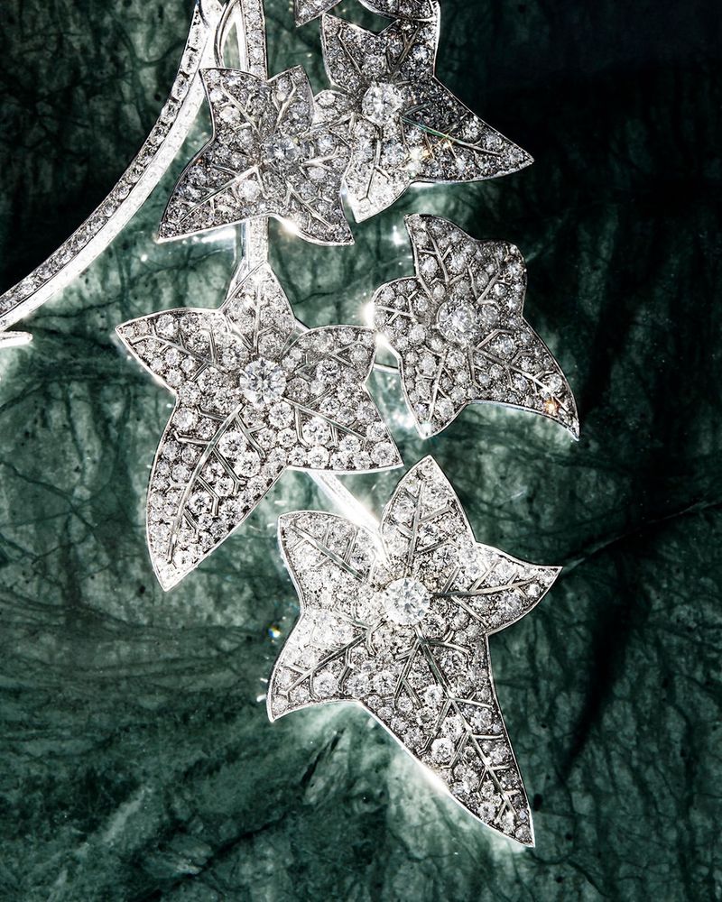 Boucheron diamond-encrusted ivy leaf necklace displayed on a dark green veined marble surface.