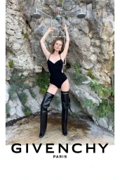 Eva Herzigova in a black bodysuit and thigh-high leather boots under an outdoor shower against a rocky cliff for Givenchy.