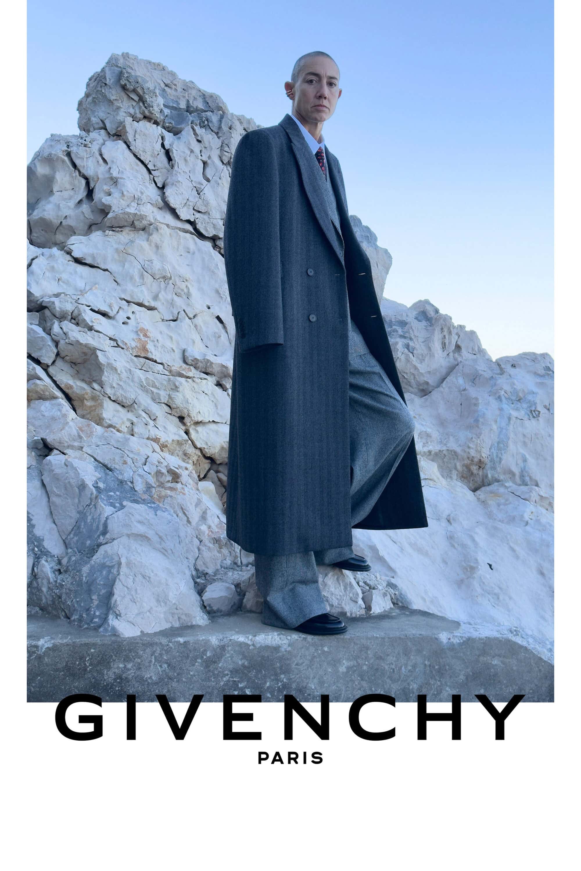 Constance Debré wearing a tailored charcoal overcoat and trousers standing on rugged white rocks for the Givenchy Winter 2026 campaign.