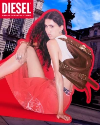 Model in a white crop top and red skirt wearing a brown leather buckled backpack in a cutout against an urban backdrop.