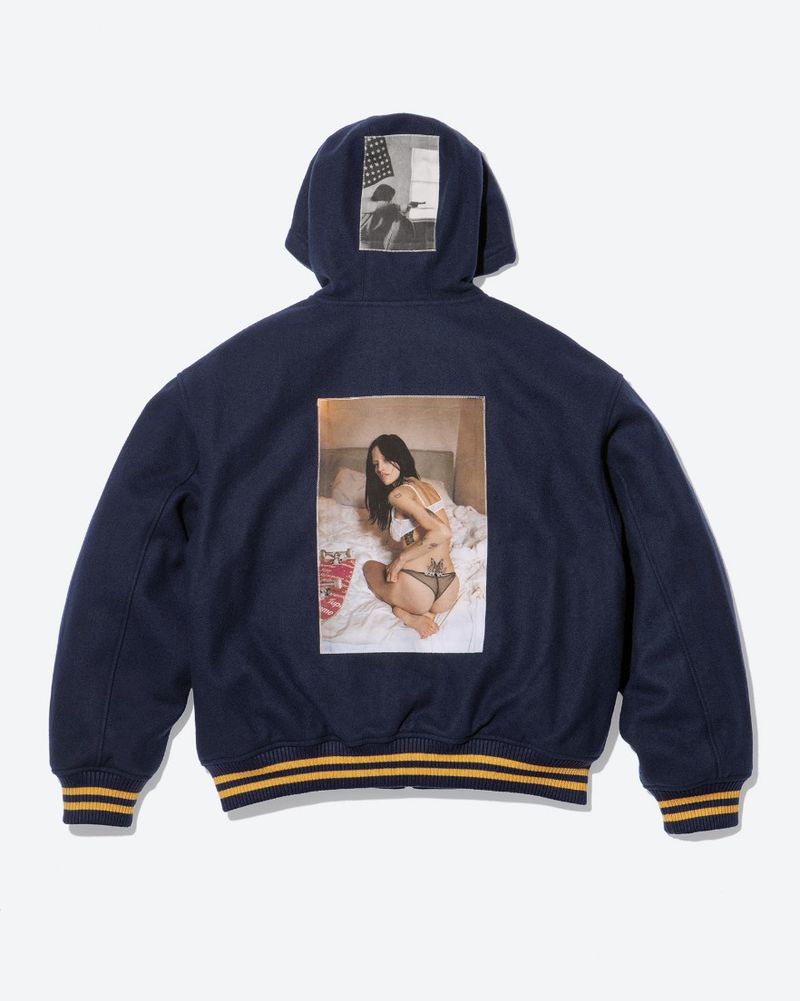 Back view of a navy blue Supreme hooded jacket featuring a Larry Clark photographic print patch on a clean studio background.