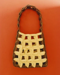Two-tone woven chain-link handbag in dark brown and cream centered against a solid warm orange background.