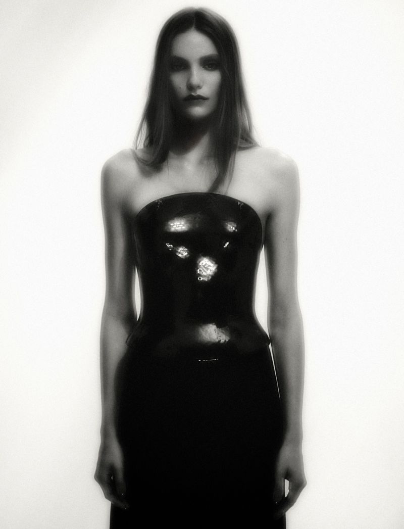 Model Taylor D posing in a glossy black strapless corset top against a bright white background for Numéro France.