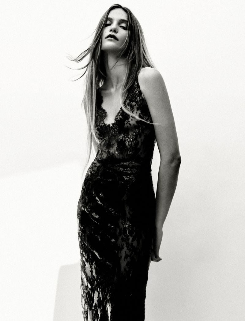 Model Taylor D poses in a sleeveless black lace gown against a bright white background in a black and white fashion portrait.