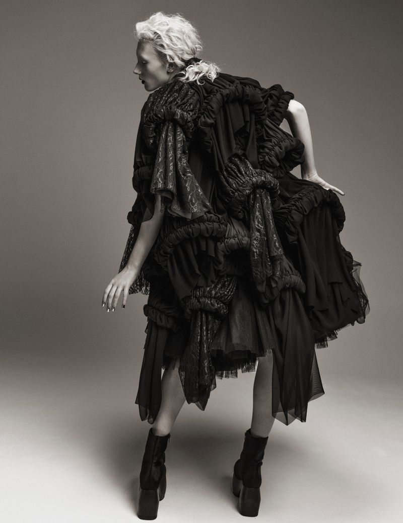 Model Ivy Stewart posing in a voluminous black ruffled Comme des Garcons dress and platform boots in a studio setting.