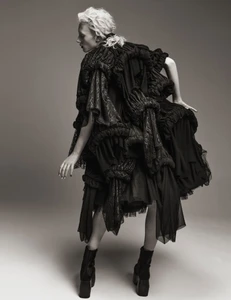 Model Ivy Stewart posing in a voluminous black ruffled Comme des Garcons dress and platform boots in a studio setting.