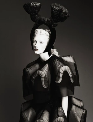 Model Ivy Stewart wearing a sculptural black Comme des Garçons outfit with an avant-garde headpiece against a grey studio backdrop.