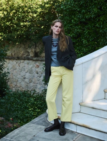 Mathilde Lakjaer in a dark blazer and pastel yellow jeans standing on outdoor marble steps for Vogue Greece.