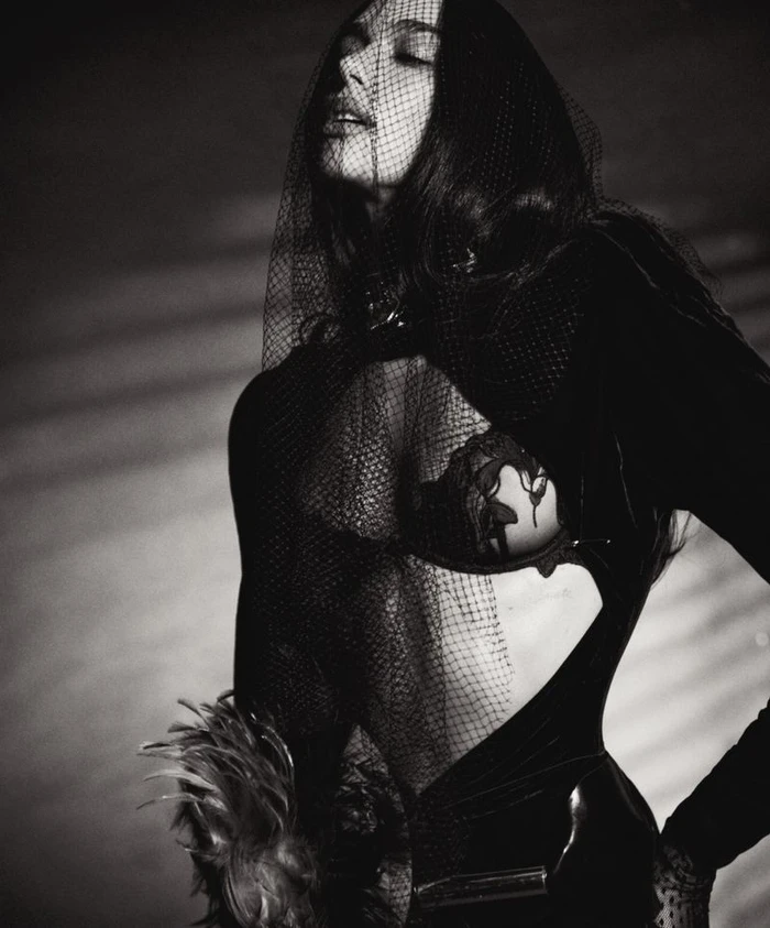 Dua Lipa wearing a black mesh veil and cutout bodysuit in a dramatic monochrome portrait for Vogue Italia.