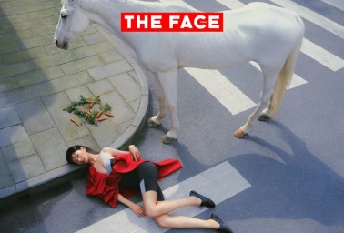 Model lying on the street next to a white horse on a painted crosswalk for The Face China editorial.