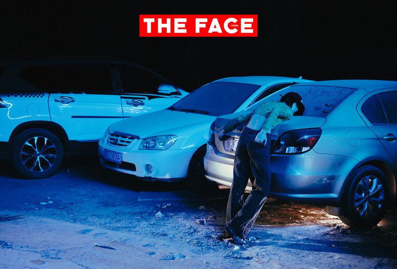 Model leaning backwards against the trunk of a silver sedan in a dimly lit parking lot at night under cool blue lighting.