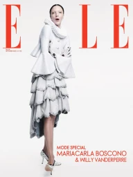 Model Mariacarla Boscono posing in an off-white ruff-collar jacket and tiered skirt against a white seamless background for Elle Belgium.