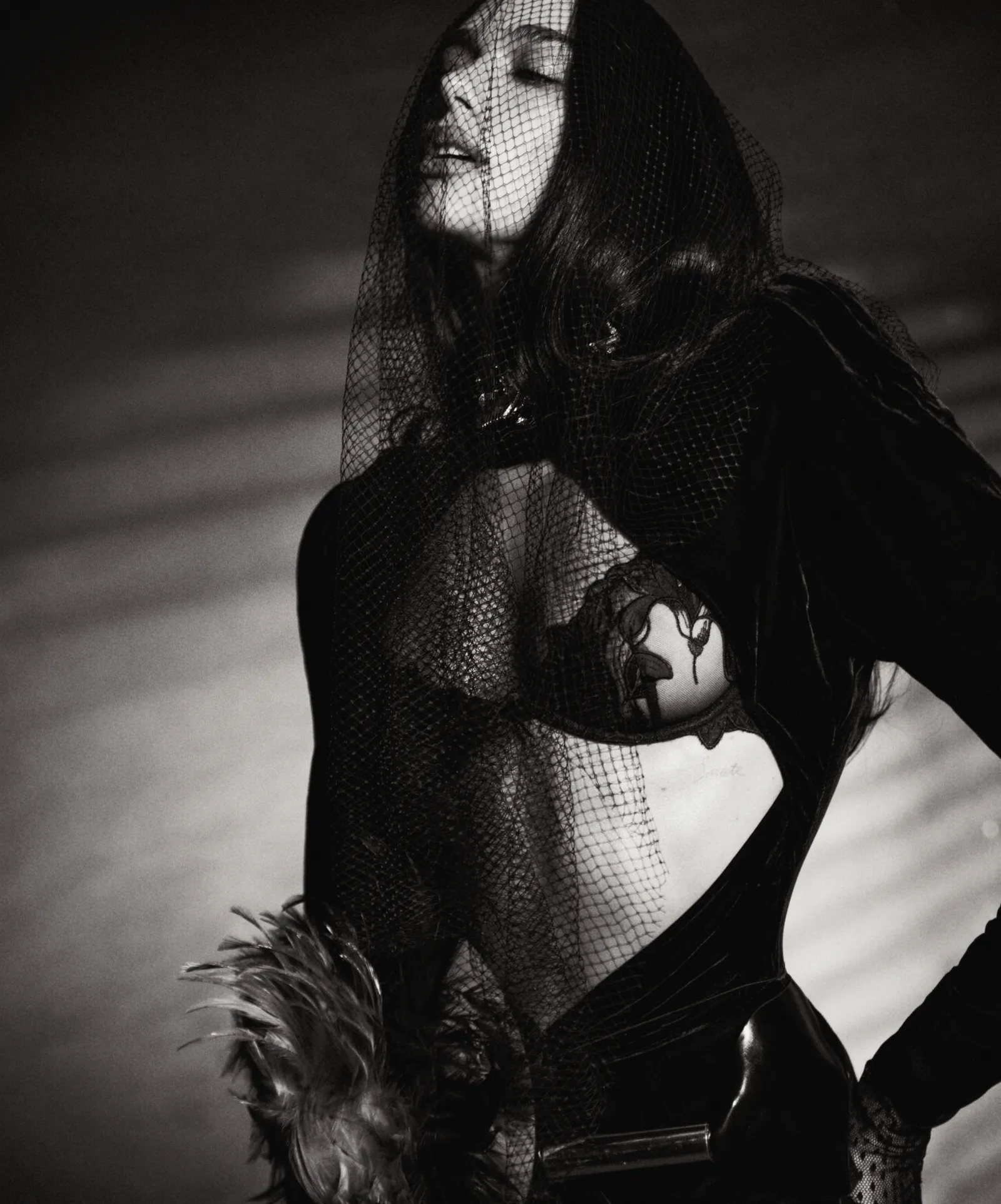 Dua Lipa wearing a sheer black mesh veil and a cutout bodysuit in a black and white editorial portrait for Vogue Italia.