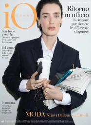 Model Marizanne Visser in a dark navy tailored blazer holding a paper coffee cup, landline phone, and documents on an iO Donna cover.