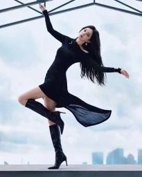 Yang Mi in a black dress and boots striking a dance pose on a rooftop for Stuart Weitzman Fall 2026